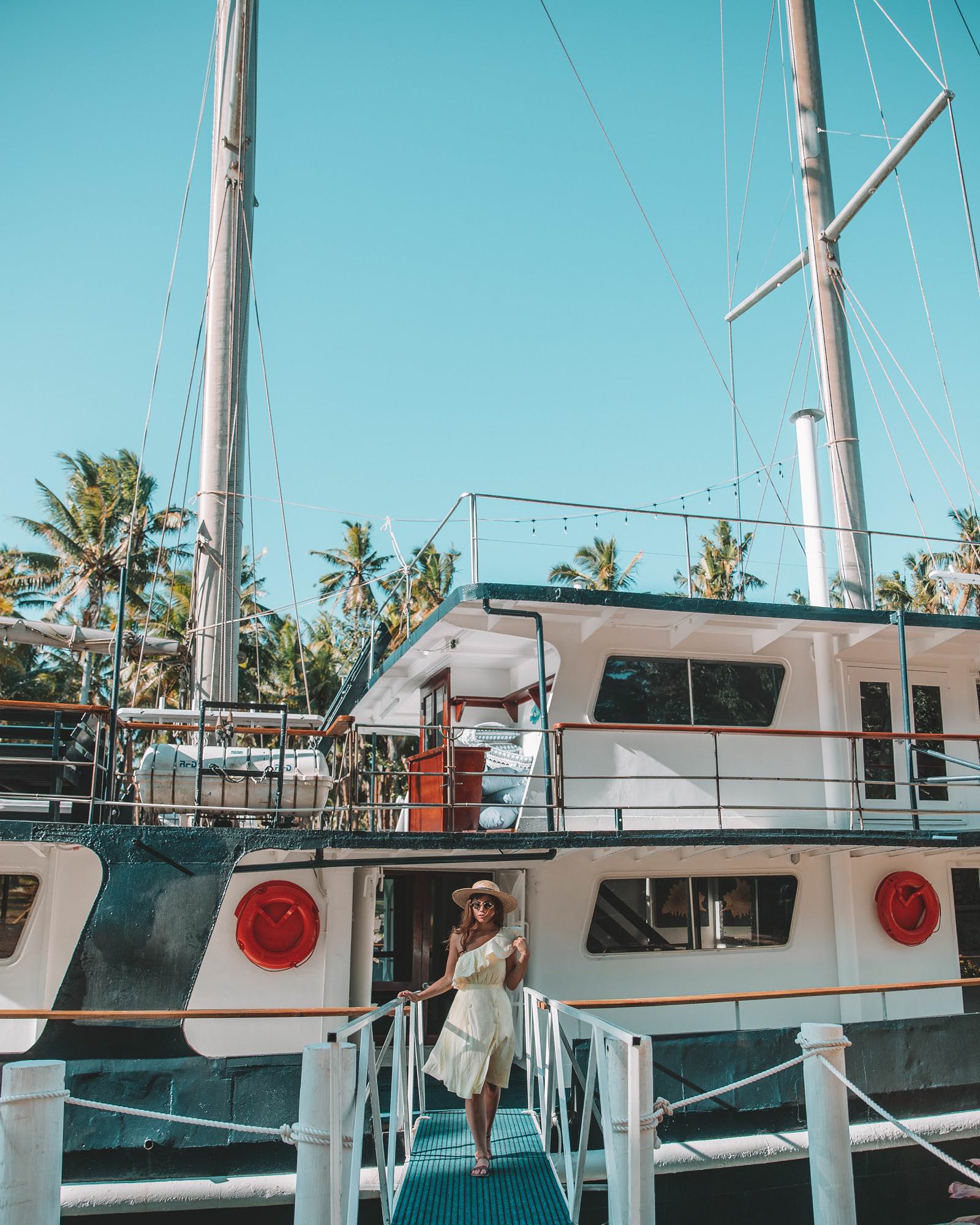 woman in sun dress walking along yacht gangplank