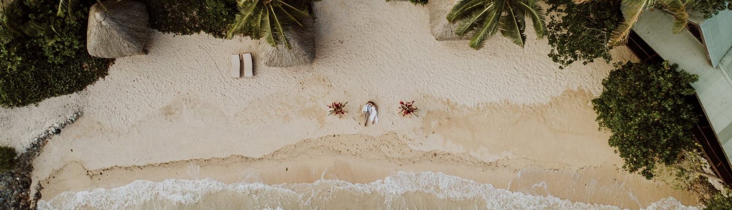 aerial view of bride and groom laying on tropical beach