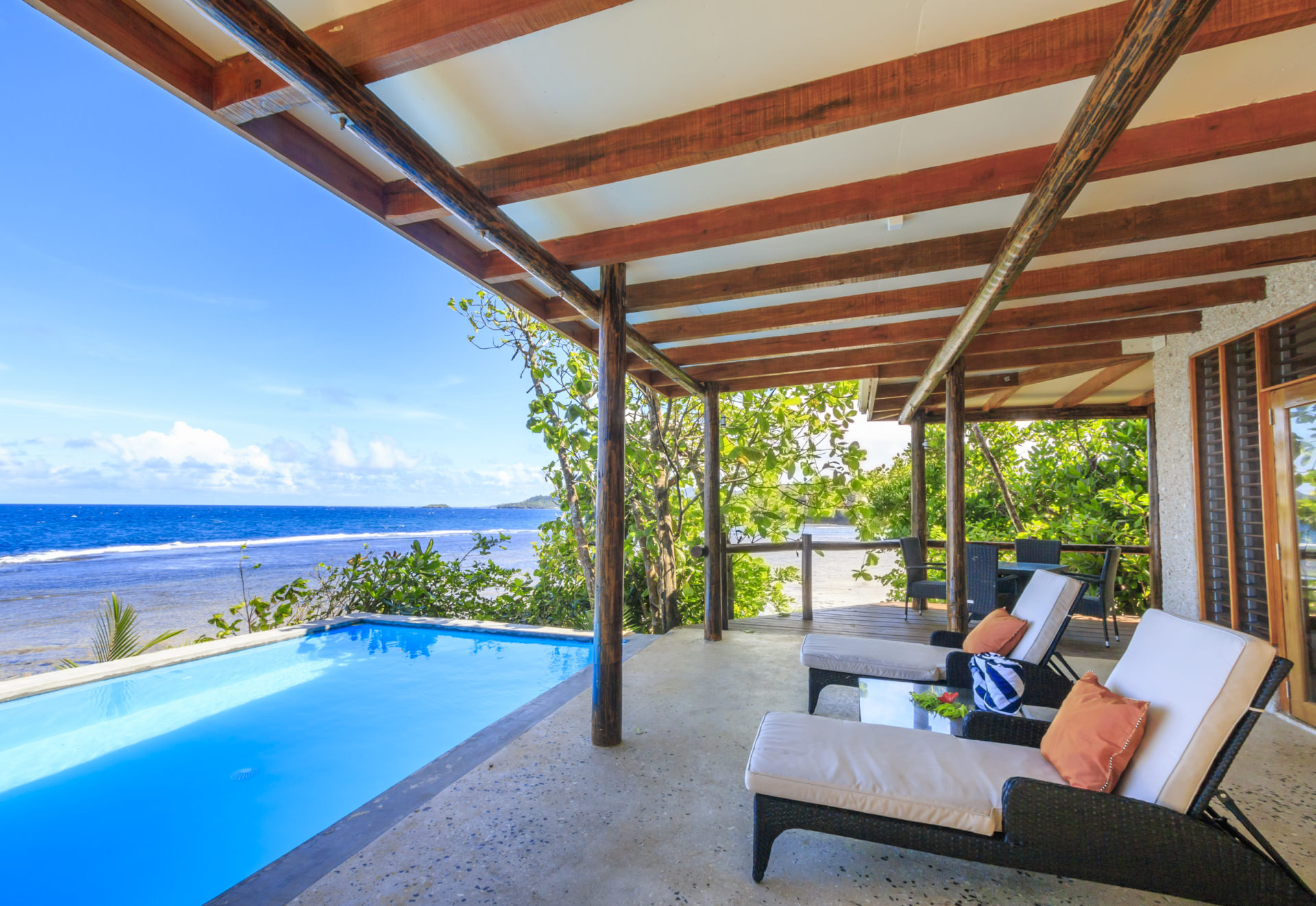 tropical villa with two lounge chairs overlooking private pool and sea view
