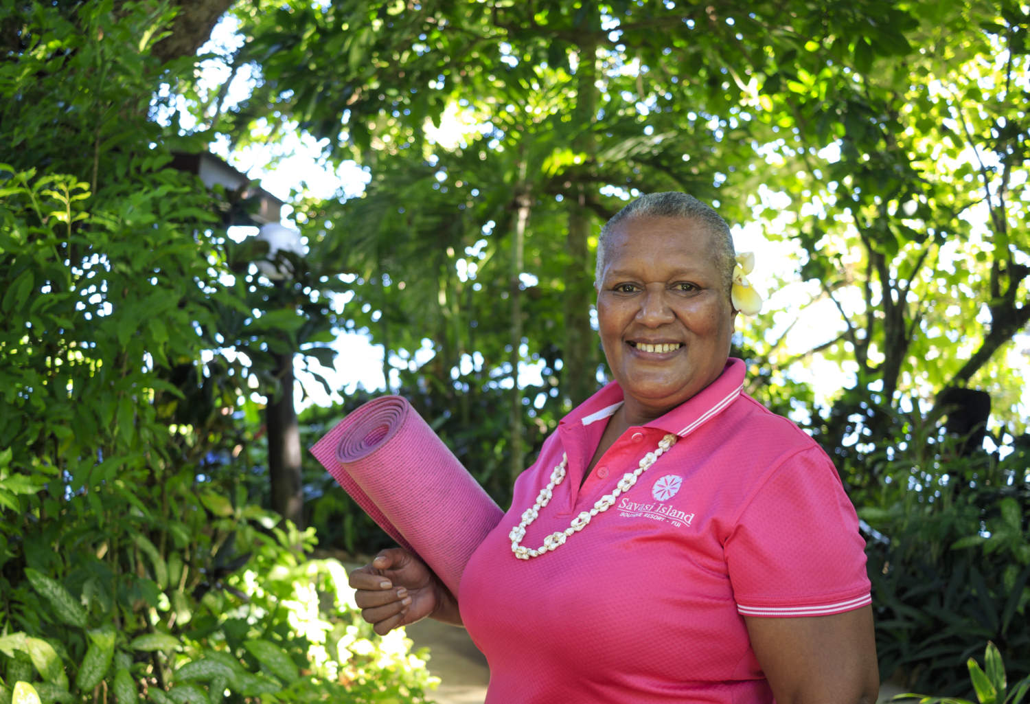 fijian woman smiling and holding pink yoga mat