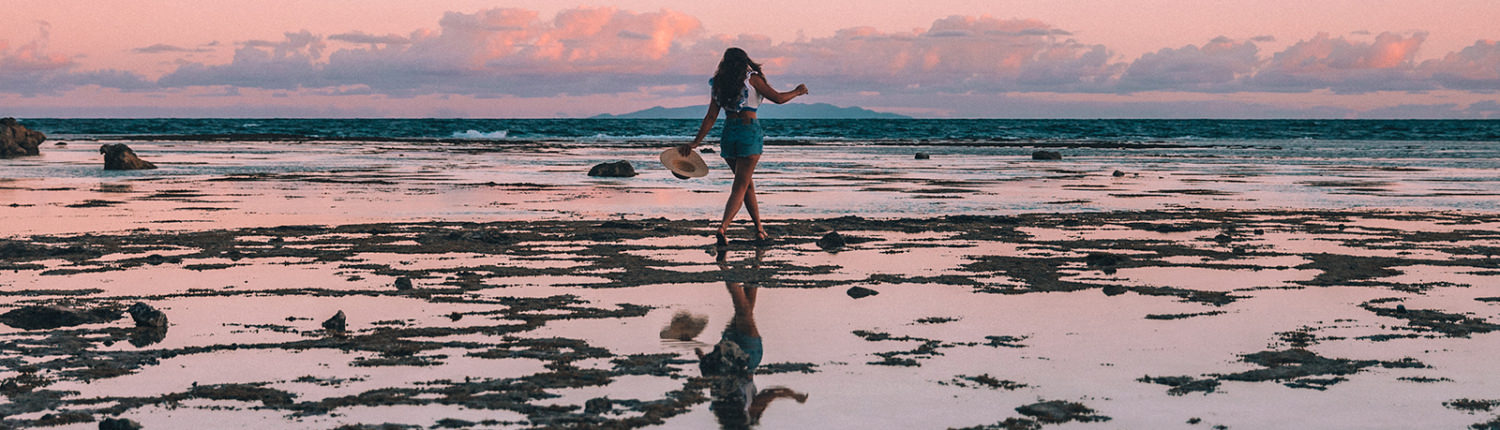woman exploring reef at low tide at sunset