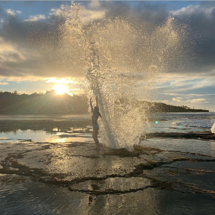 woman standing by natural blowhole at sunset