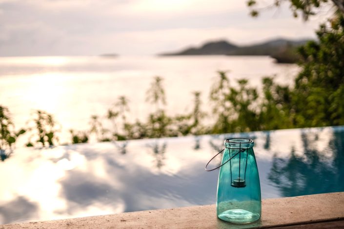 Blue lantern set beside swimming pool overlooking sunset