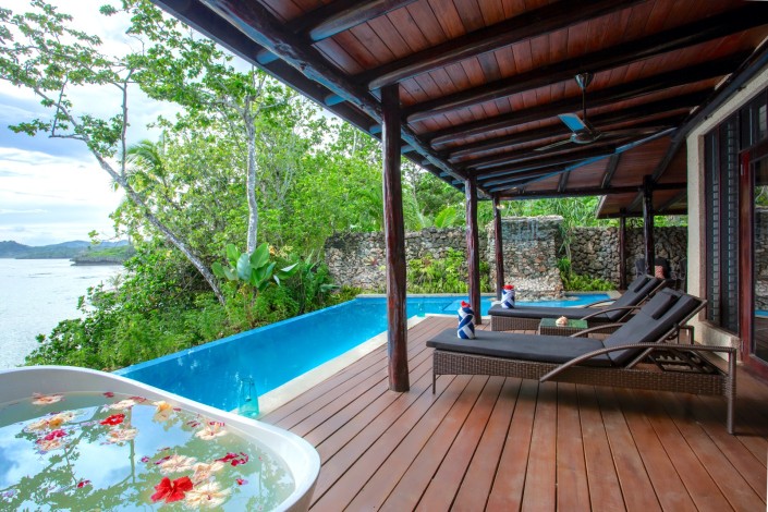 Tropical view from villa style accommodation overlooking a private pool and an outdoor bath