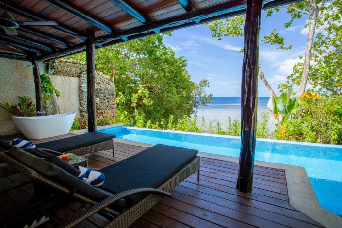 Tropical view of two sunloungers beside a private swimming pool overlooking the ocean