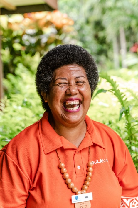 Portrait of Fijian woman laughing in bright orange polo shirt