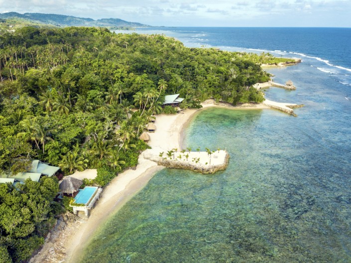 Aerial view of private island resort in Fiji with villas dotted along the shoreline