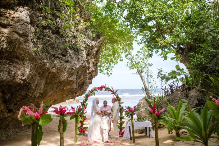 Outdoor elopement on a private beach surrounded by foliage and tropical flowers